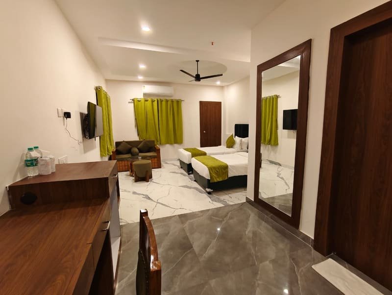 A room with a writing desk, mirror and bed beyond